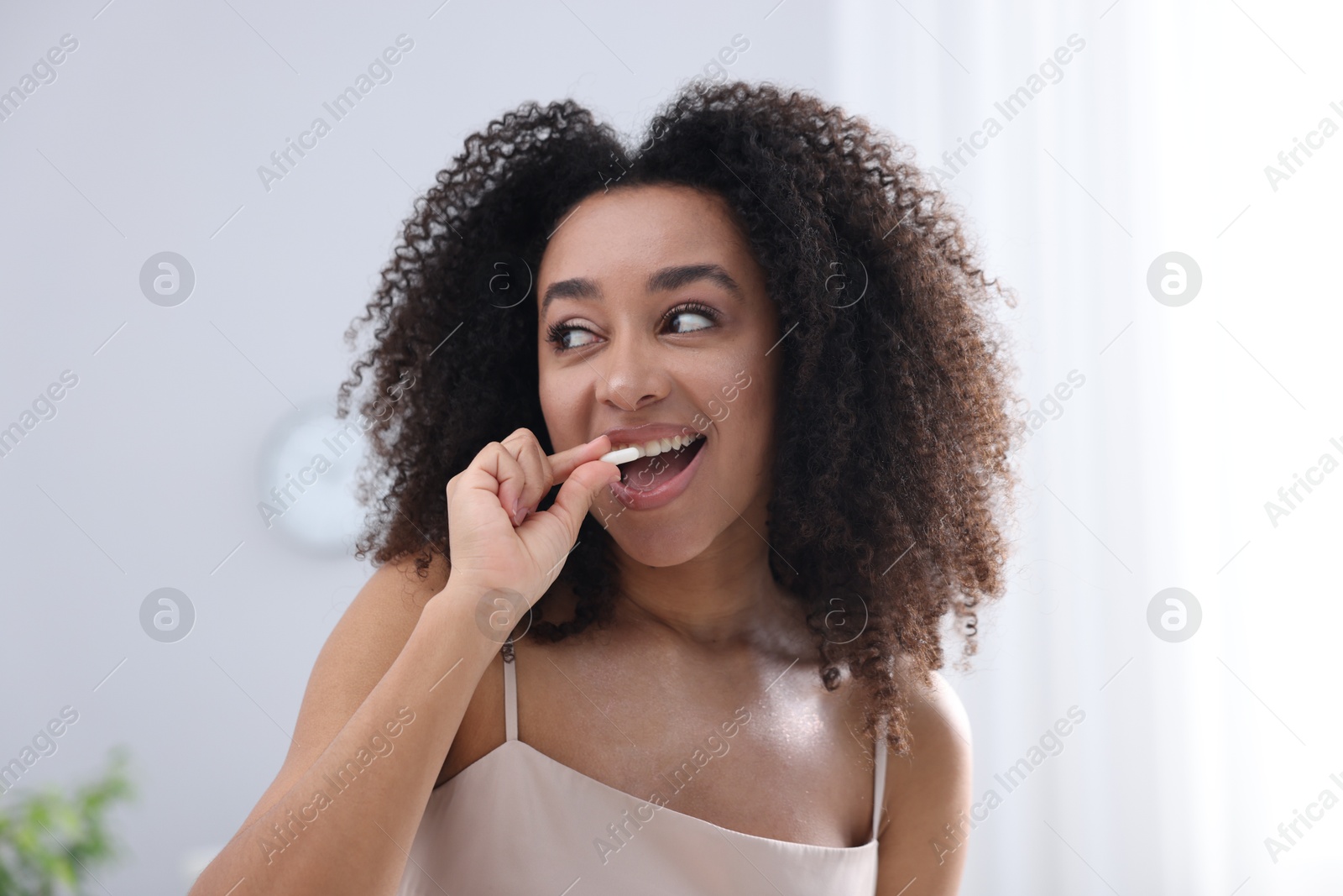 Beautiful Brazilian woman with collagen pill indoors Photo of Beautiful Brazilian woman with collagen pill indoors