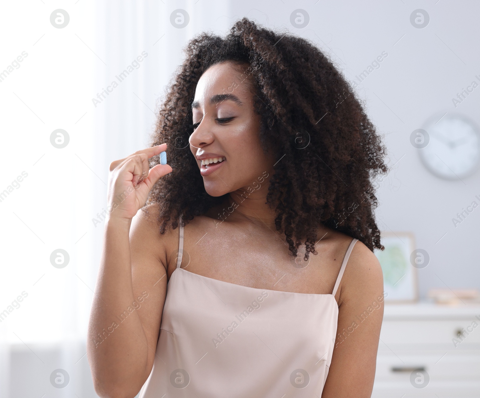 Beautiful Brazilian woman taking collagen pill indoors Photo of Beautiful Brazilian woman taking collagen pill indoors