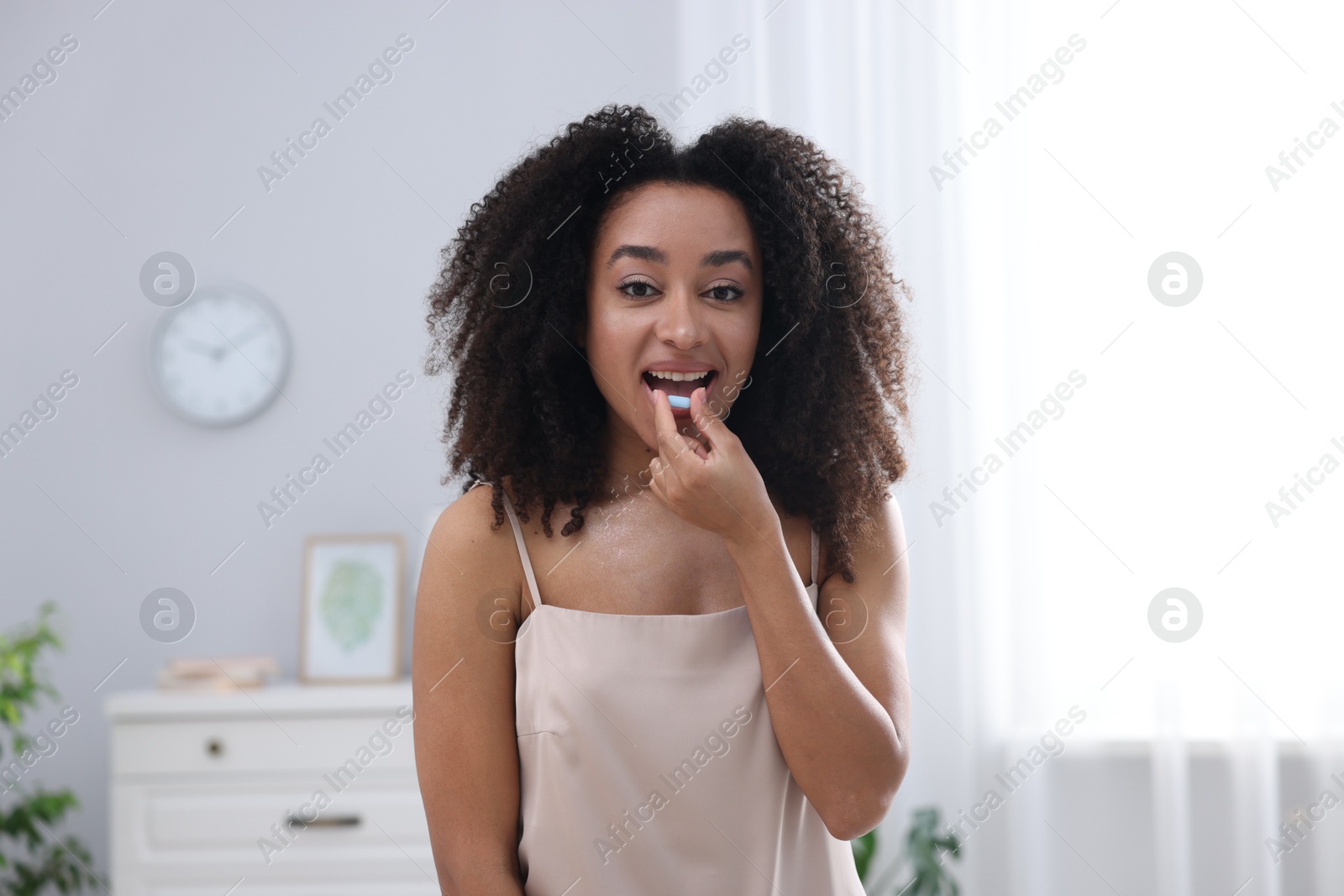 Beautiful Brazilian woman taking collagen pill indoors Photo of Beautiful Brazilian woman taking collagen pill indoors