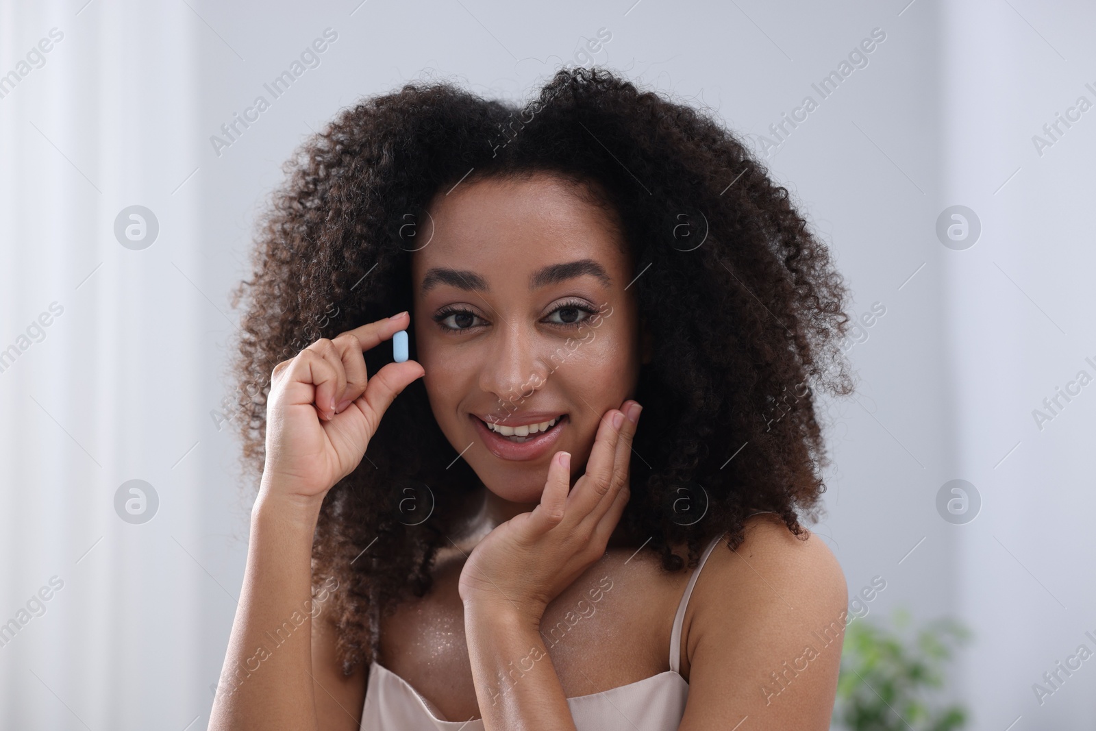 Beautiful Brazilian woman with collagen pill indoors Photo of Beautiful Brazilian woman with collagen pill indoors