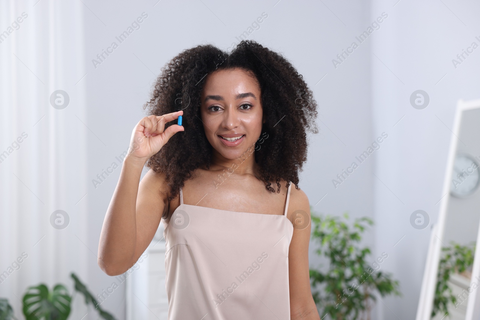 Beautiful Brazilian woman with collagen pill indoors Photo of Beautiful Brazilian woman with collagen pill indoors