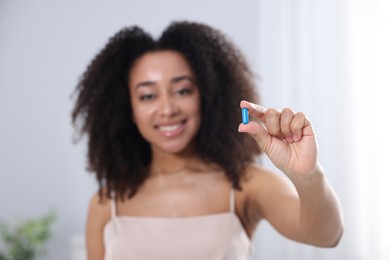 Photo of Beautiful Brazilian woman with collagen pill indoors, selective focus