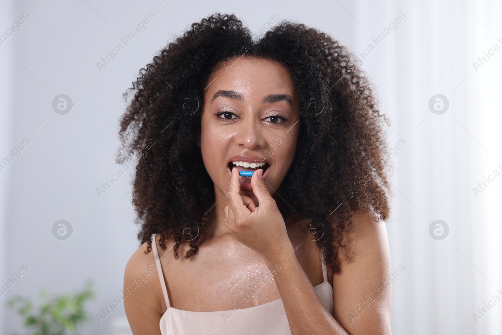 Beautiful Brazilian woman taking collagen pill indoors Photo of Beautiful Brazilian woman taking collagen pill indoors