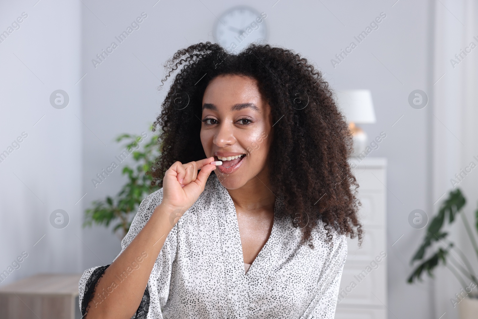 Beautiful Brazilian woman taking collagen pill indoors Photo of Beautiful Brazilian woman taking collagen pill indoors