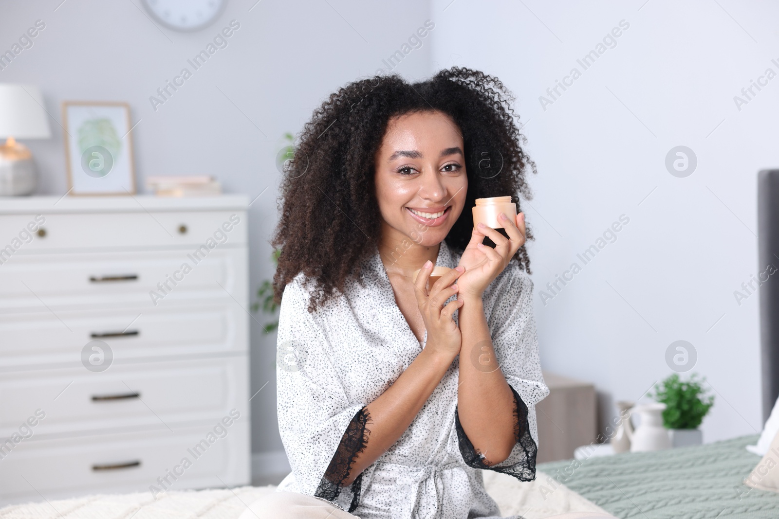Beautiful Brazilian woman with jar of collagen cream indoors Photo of Beautiful Brazilian woman with jar of collagen cream indoors
