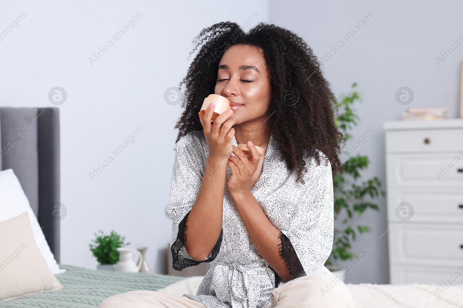 Beautiful Brazilian woman with jar of collagen cream indoors Photo of Beautiful Brazilian woman with jar of collagen cream indoors