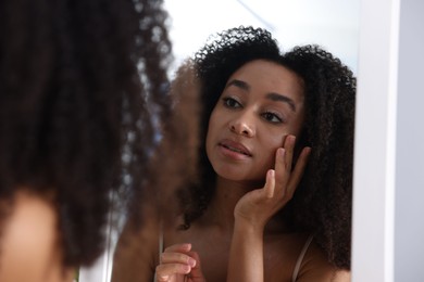 Photo of Beautiful Brazilian woman with healthy skin looking at mirror indoors