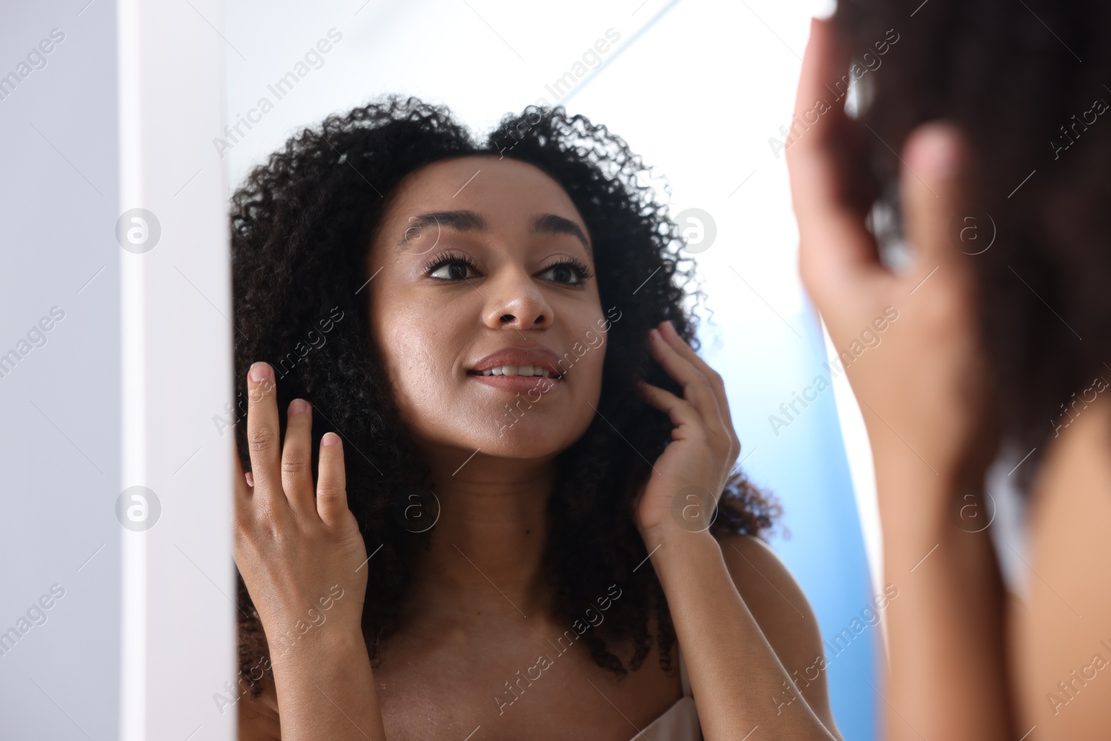 Beautiful Brazilian woman with healthy skin looking at mirror indoors Photo of Beautiful Brazilian woman with healthy skin looking at mirror indoors