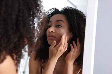 Photo of Beautiful Brazilian woman with healthy skin looking at mirror indoors