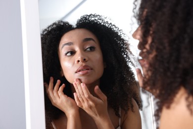 Photo of Beautiful Brazilian woman with healthy skin looking at mirror indoors