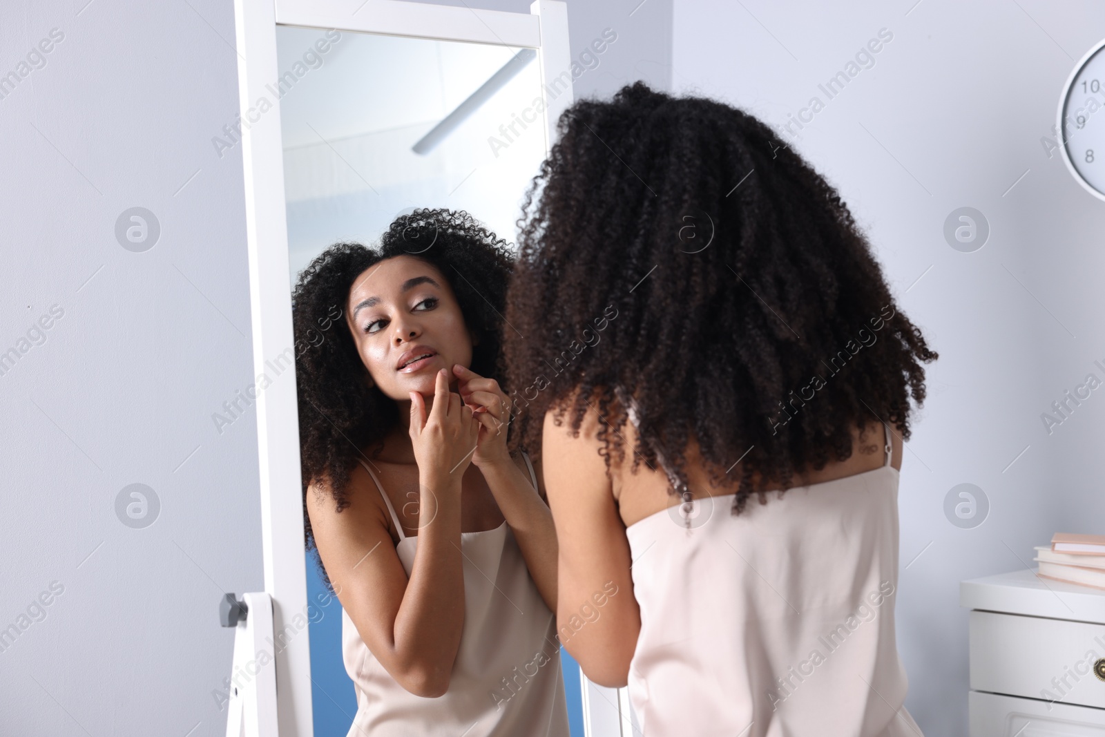 Beautiful Brazilian woman with healthy skin looking at mirror indoors Photo of Beautiful Brazilian woman with healthy skin looking at mirror indoors