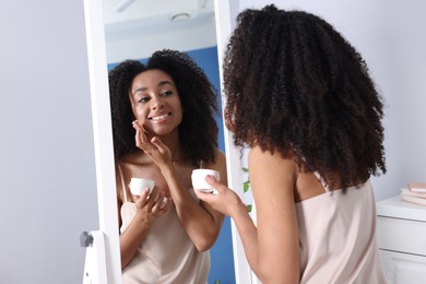 Photo of Beautiful Brazilian woman with healthy skin looking at mirror indoors