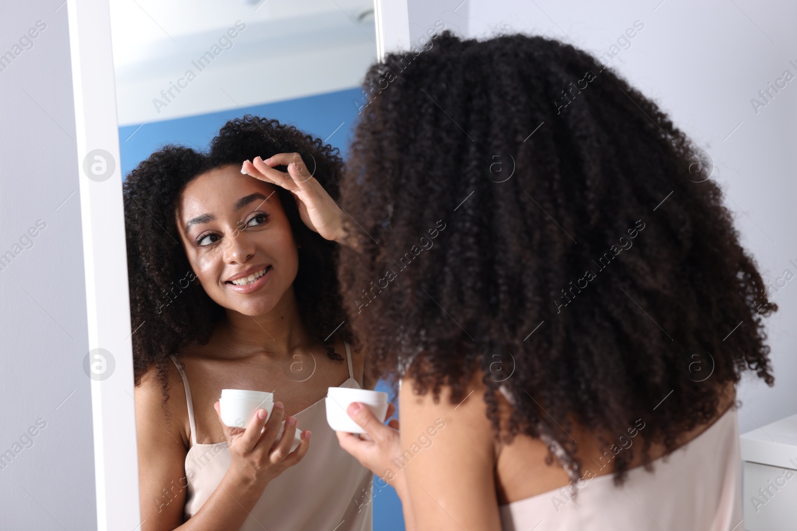 Beautiful Brazilian woman with healthy skin looking at mirror indoors Photo of Beautiful Brazilian woman with healthy skin looking at mirror indoors