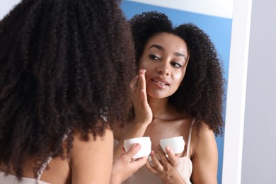 Photo of Beautiful Brazilian woman with healthy skin looking at mirror indoors