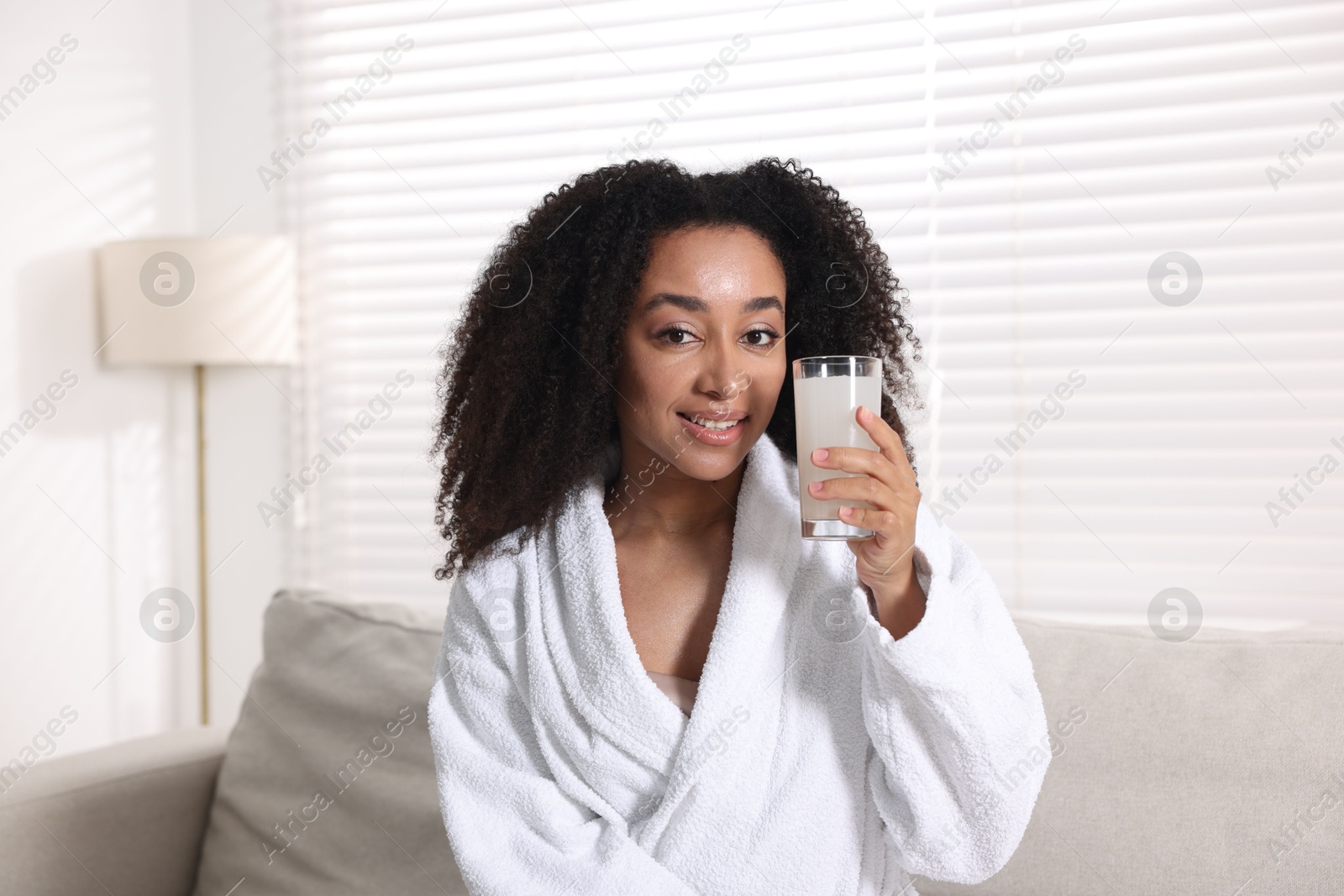 Beautiful Brazilian woman with glass of collagen water indoors Photo of Beautiful Brazilian woman with glass of collagen water indoors