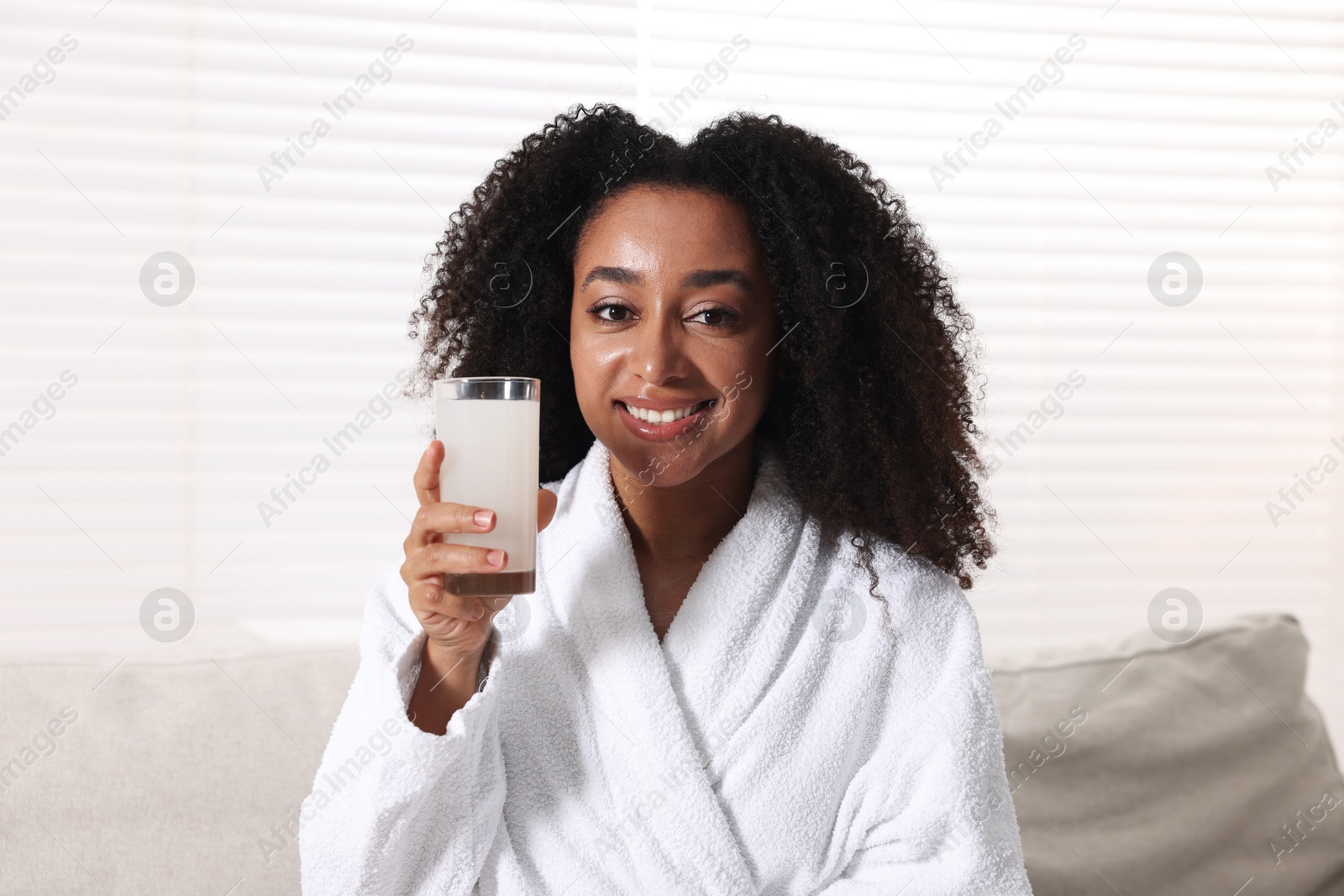 Beautiful Brazilian woman with glass of collagen water indoors Photo of Beautiful Brazilian woman with glass of collagen water indoors