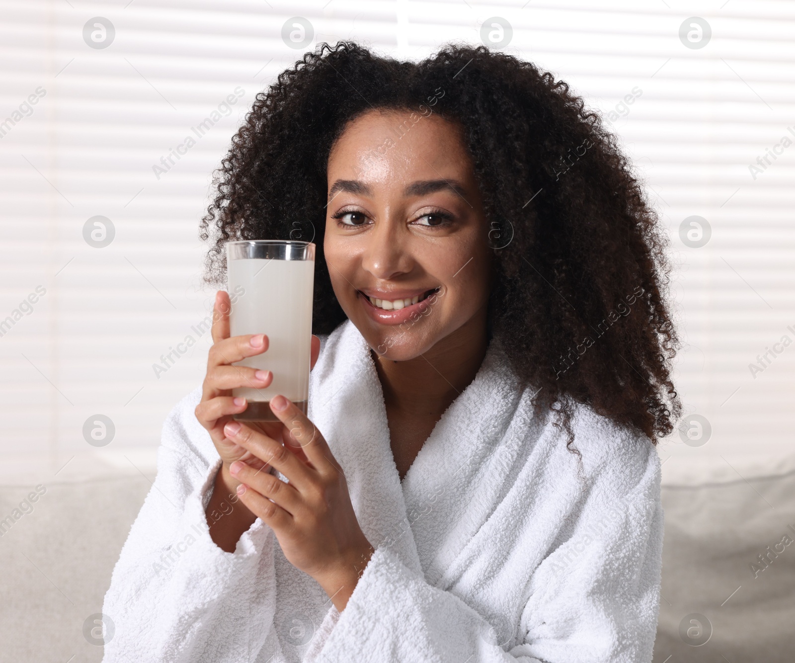 Beautiful Brazilian woman with glass of collagen water indoors Photo of Beautiful Brazilian woman with glass of collagen water indoors