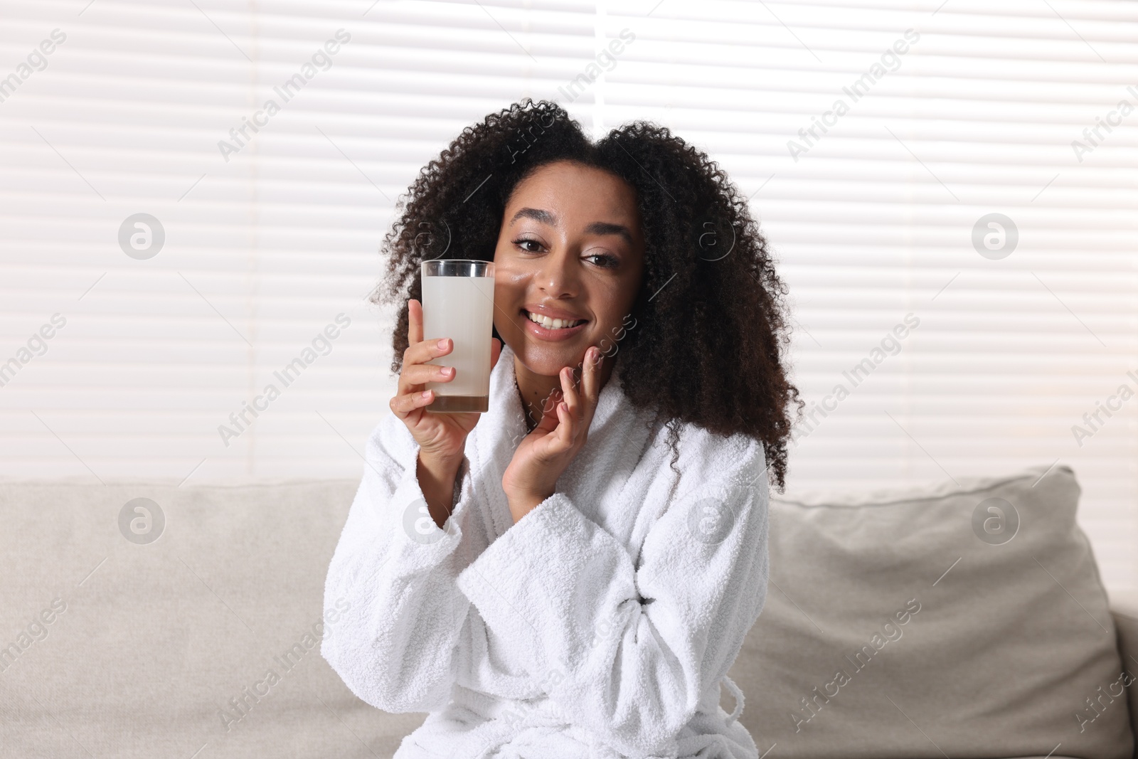 Beautiful Brazilian woman with glass of collagen water indoors Photo of Beautiful Brazilian woman with glass of collagen water indoors