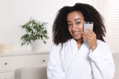 Photo of Beautiful Brazilian woman with glass of collagen water indoors. Space for text