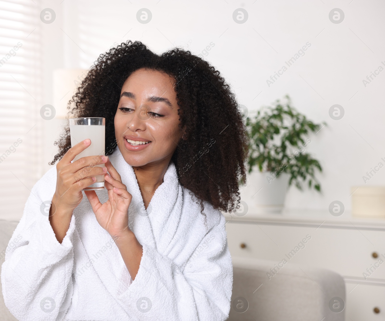 Beautiful Brazilian woman with glass of collagen water indoors Photo of Beautiful Brazilian woman with glass of collagen water indoors