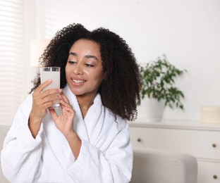 Photo of Beautiful Brazilian woman with glass of collagen water indoors