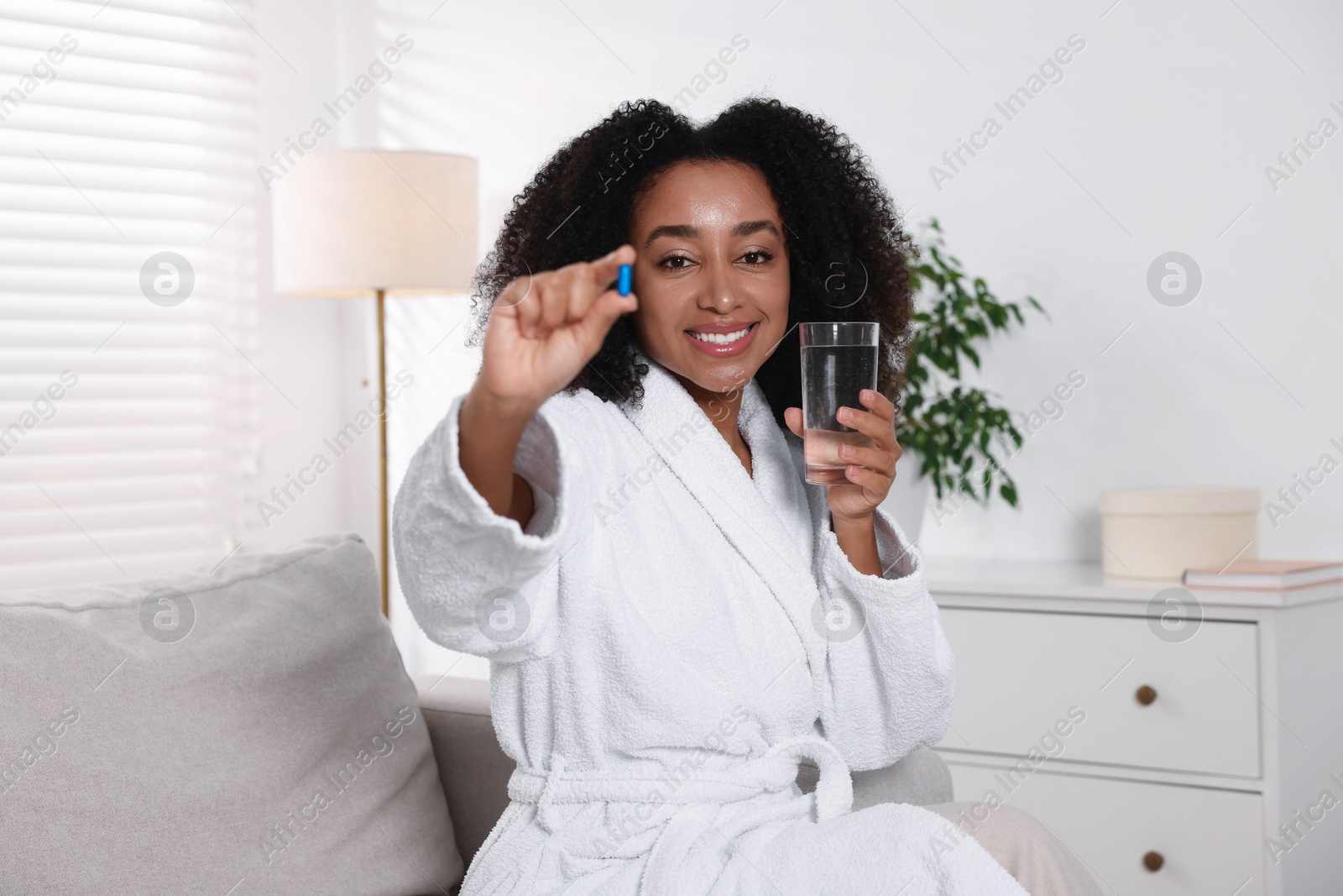 Beautiful Brazilian woman with glass of water and collagen pill indoors Photo of Beautiful Brazilian woman with glass of water and collagen pill indoors