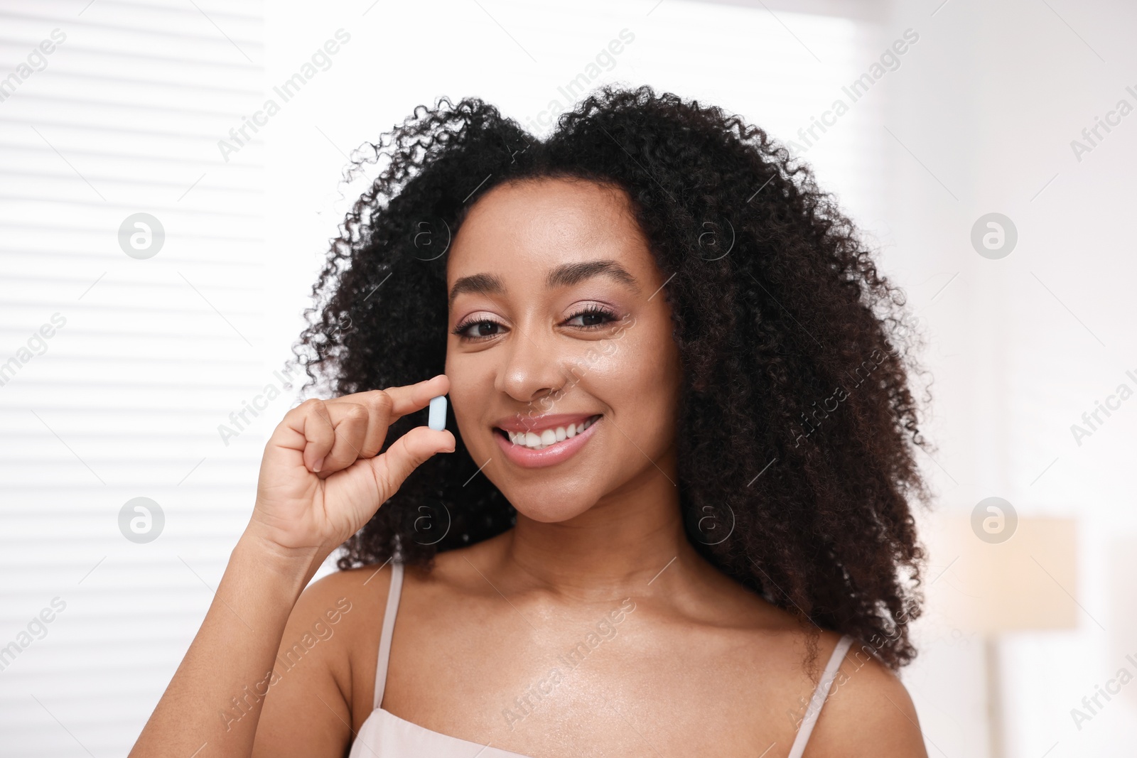 Beautiful Brazilian woman with collagen pill indoors Photo of Beautiful Brazilian woman with collagen pill indoors