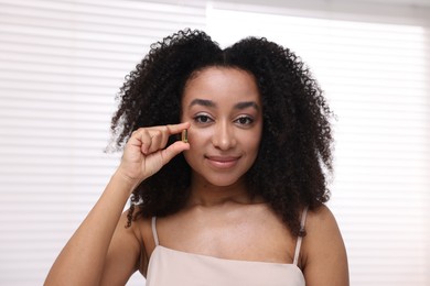 Photo of Beautiful Brazilian woman with collagen pill indoors