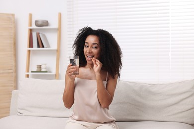 Photo of Beautiful Brazilian woman with glass of water taking collagen pill indoors