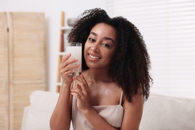 Photo of Beautiful Brazilian woman with glass of collagen water indoors