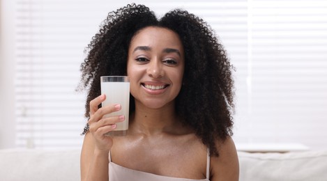 Photo of Beautiful Brazilian woman with glass of collagen water indoors