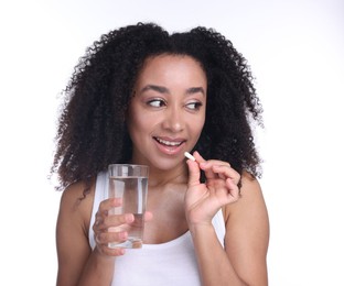 Photo of Beautiful Brazilian woman with glass of water and collagen pill on white background