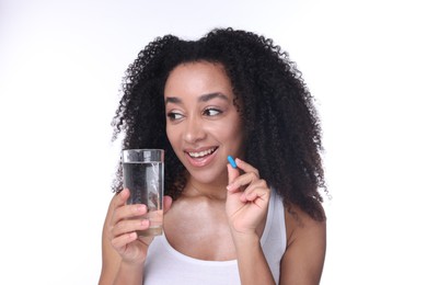 Photo of Beautiful Brazilian woman with glass of water and collagen pill on white background