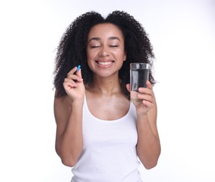 Photo of Beautiful Brazilian woman with glass of water and collagen pill on white background