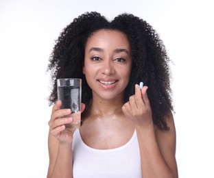 Photo of Beautiful Brazilian woman with glass of water and collagen pill on white background
