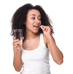 Photo of Beautiful Brazilian woman with glass of water taking collagen pill on white background