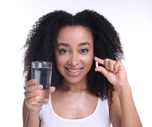 Photo of Beautiful Brazilian woman with glass of water and collagen pill on white background