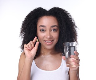 Photo of Beautiful Brazilian woman with glass of water and collagen pill on white background
