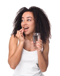 Photo of Beautiful Brazilian woman with glass of water taking collagen pill on white background