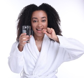 Photo of Beautiful Brazilian woman with glass of water and collagen pill on white background