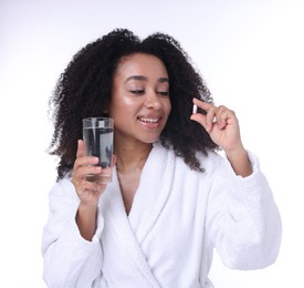 Photo of Beautiful Brazilian woman with glass of water and collagen pill on white background