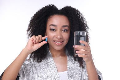 Photo of Beautiful Brazilian woman with glass of water and collagen pill on white background