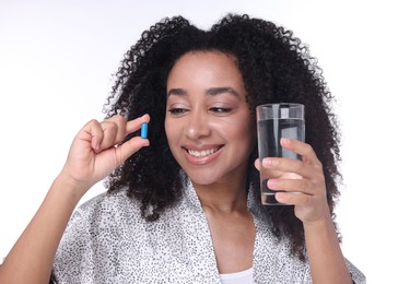 Photo of Beautiful Brazilian woman with glass of water and collagen pill on white background