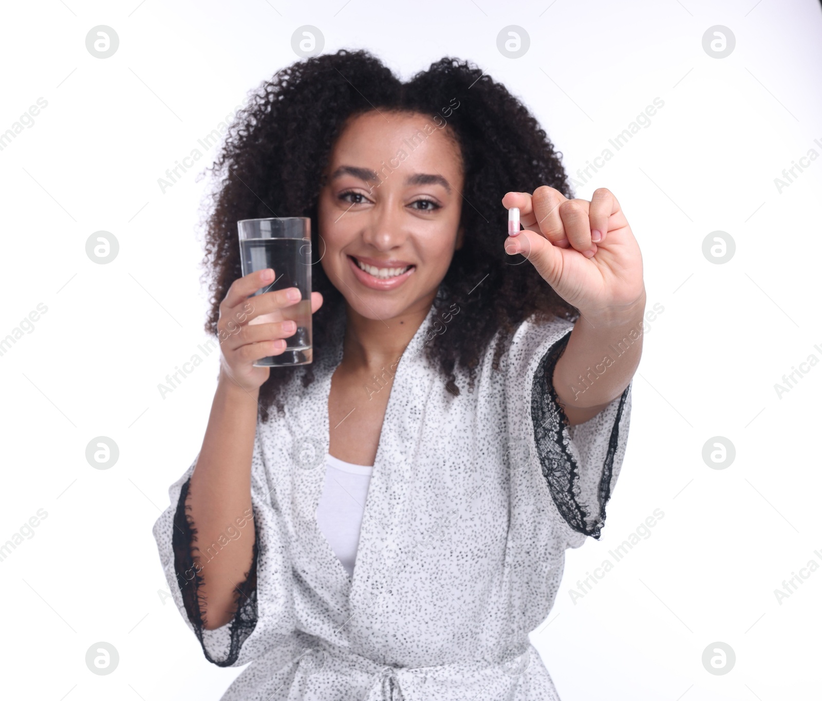 Beautiful Brazilian woman with glass of water and collagen pill on white background Photo of Beautiful Brazilian woman with glass of water and collagen pill on white background