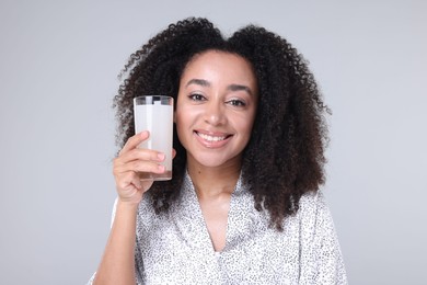 Photo of Beautiful Brazilian woman with glass of collagen water on gray background