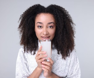 Photo of Beautiful Brazilian woman with glass of collagen water on gray background