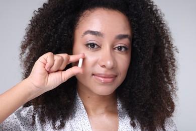 Photo of Beautiful Brazilian woman with collagen pill on gray background, closeup