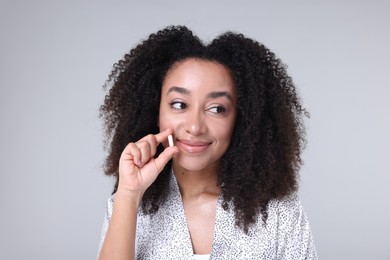 Photo of Beautiful Brazilian woman with collagen pill on gray background