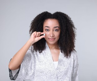 Photo of Beautiful Brazilian woman with collagen pill on gray background