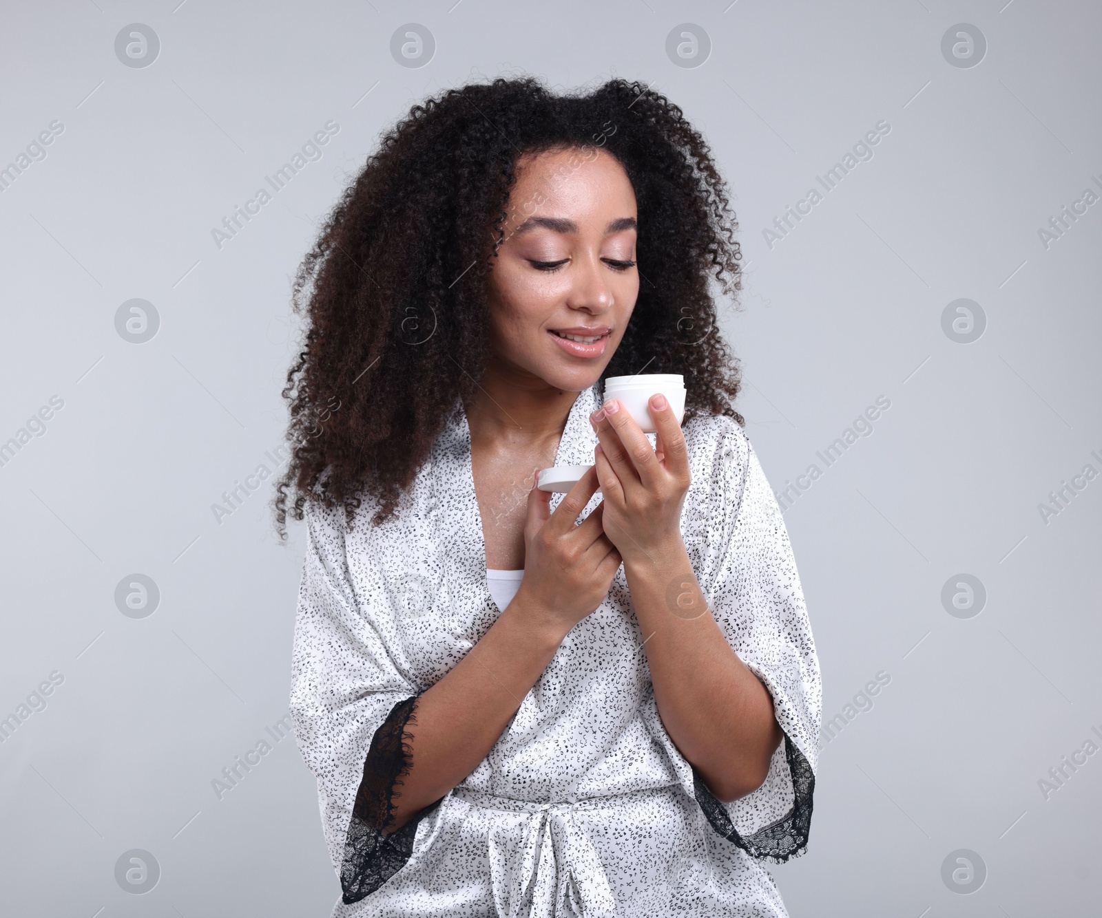 Beautiful Brazilian woman with jar of collagen cream on gray background Photo of Beautiful Brazilian woman with jar of collagen cream on gray background